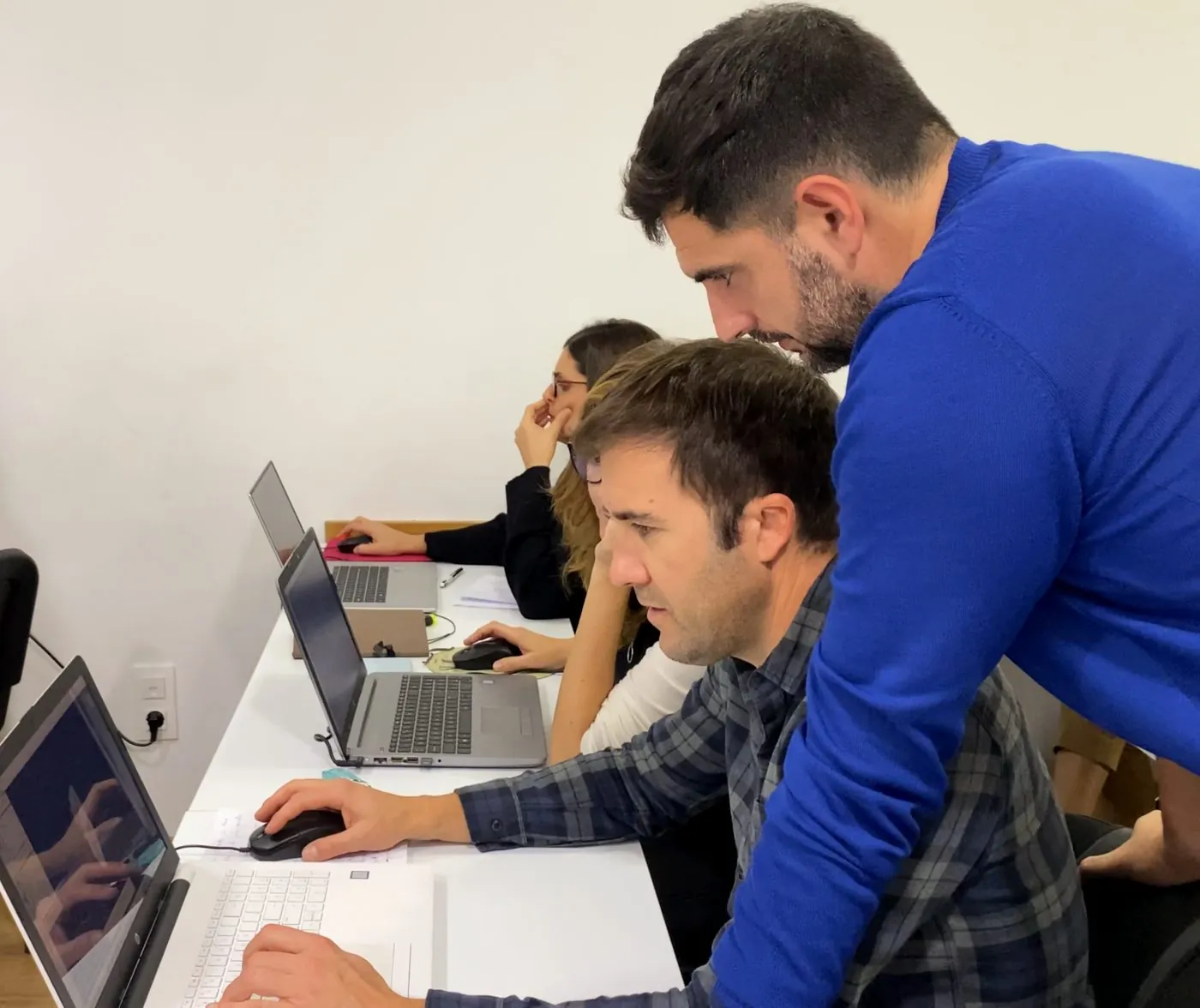 Curso presencial de impressão 3D de palmilhas: formador a ajudar um formando ao portátil, com uma impressora Bambu Lab ao fundo