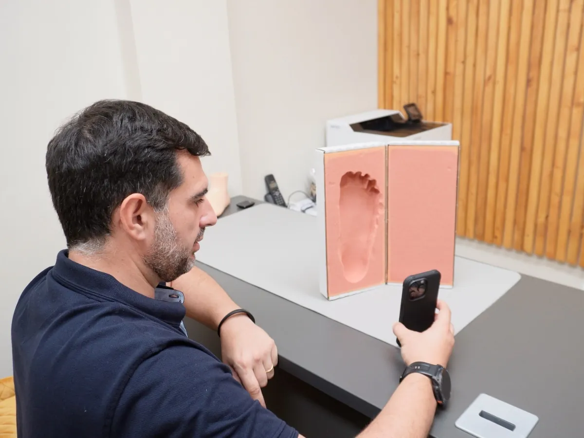 Podologista a digitalizar em 3D com o telemóvel a impressão de um pé no consultório